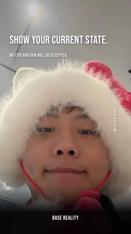 Base Reality mission 5, "Show your current state.", answered with a deadpan selfie in a white fur hat with a pink bow.